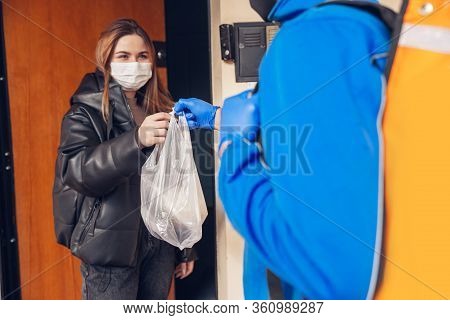 Contacless Delivery Service During Quarantine. Man Delivers Food And Shopping Bags During Isolation.