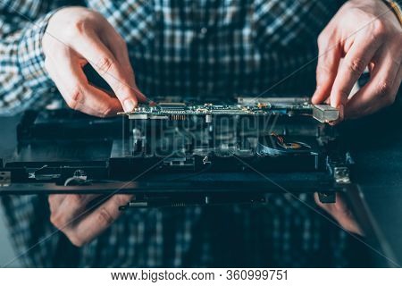 Electronic Engineering. Computer Maintenance. Male Technician Examining Disassembled Laptop.