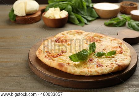 Delicious Khachapuri With Cheese And Basil On Wooden Table