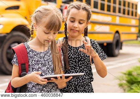 Cheerful Little Girls Next To School Bus. Backback. Back To School Concept.