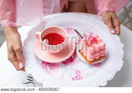 Sugar Pink Cube Ball Velours Mousse Cake Dessert On Plate With Cup Of Tea In Cropped Woman Hands. Ca