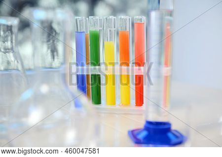 Focus On Test Tubes With Rainbow Colored Chemicals And Reagents Standing On Tripod. Blurred Foregrou