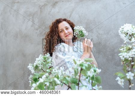 Woman Long Curly Hair In White Embroidered Ukrainian Shirt. Defocused Focus On Foreground On Blossom