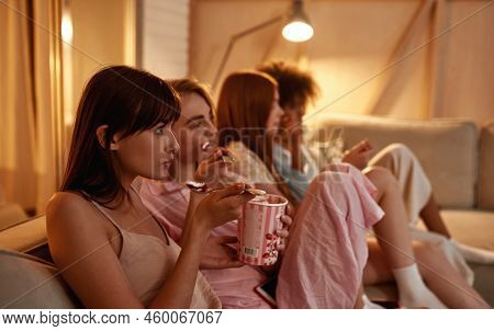 Young Multiethnic Girlfriends Eating Ice Cream And Watching Tv Or Movie On Sofa During Girlish Sleep