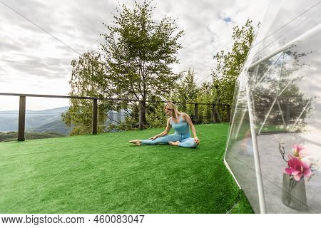 A Woman Is Doing Exercises On The Terrace Of A Transparent Bubble Dome