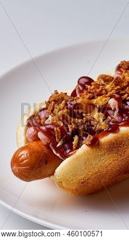 Hotdog With Barbecue Sauce And Bacon On A White Plate On A White Background