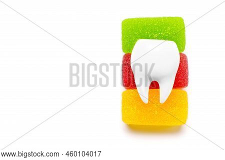 Large White Tooth Model Placed On Top Of Colorful Jelly Candies Isolated On White Background With Co