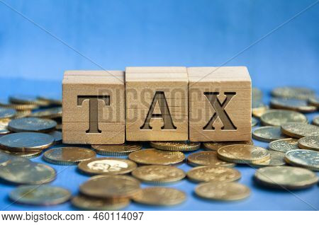 Tax Word Engraved On Wooden Block Surrounded With Gold Coins. Taxation Concept.