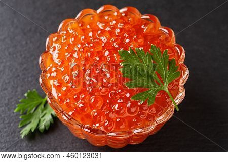 Salmon Red Caviar In A Glass Bowl On A Black Background. Crystal Dish Full Of Trout Caviar Close-up.