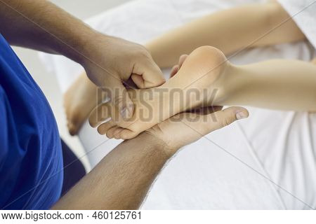 Reflexologist And Acupressure Therapy Professional Doing Foot Massage To Young Woman