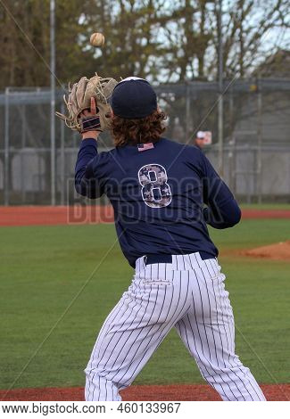 A Baseball Player Playing Third Base Catching A Ball During Warmups In Between Innings Of A Baseball