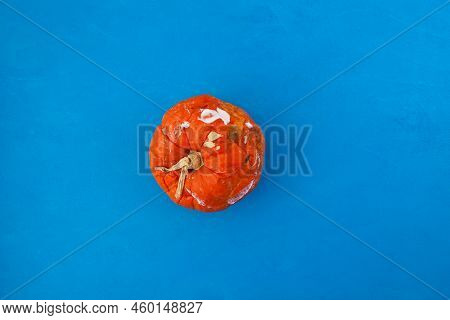 Rotten Spoiled Pumpkin On Blue Blotchy Background. Ugly Moldy Vegetable. Top View, Selective Focus. 