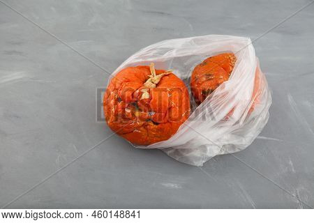 Rotten Spoiled Pumpkins In Plastic Bag On Grey Blotchy Background. Ugly Moldy Vegetable. Close-up, S