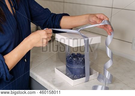 Hands Of Female Bakery Chef Or Saleswoman Packing Cake Into Gift Box. Young Adult Woman In Apron Hol