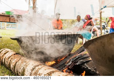 Unrecognizable Indigenous People Preparing A Broth Over A Pot On A Campfire Made With Palm Wood