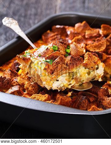 Close-up Of Scalloped Chicken Casserole Topped With Croutons In Baking Dish On Dark Wooden Table Wit