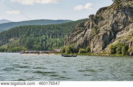 Fishing Wooden Longboat With Man Floating Along Cliff Near Tent Camp In Village Of Katun.chivyrkuisk