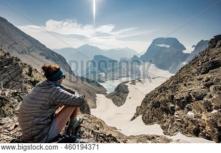 Woman In Puffy Coat Looks Out Over Grinnell Glacier On Smoky Day In Glacier National Park