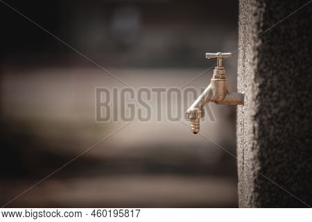 Selective Blur On A Dripping Tap, A Leaking Faucet, Old Style, Wasting Water Ressources In Summer Du
