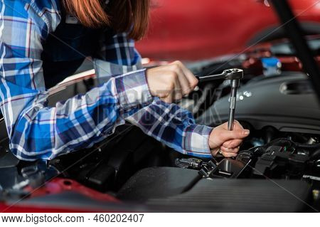 Female Auto Mechanic Unscrewing A Nut To Replace A Car Spark Plug.