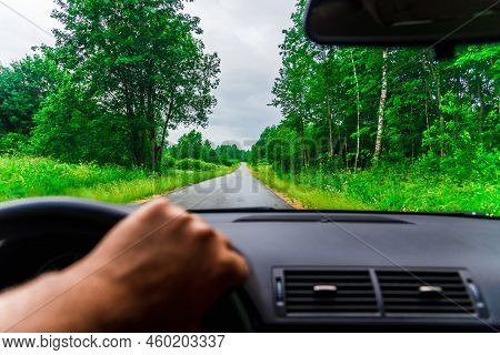 View Of The Road Through The Windshield Of The Car.driver's Hand On Steering Wheel At Forest Rainy S