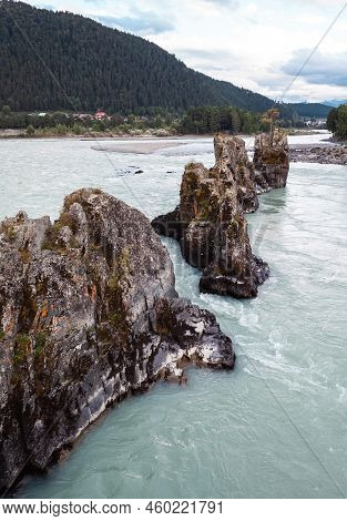 A Fast-flowing Wide And Full-flowing Mountain River. Large Rocks Stick Out Of The Water. Big Mountai