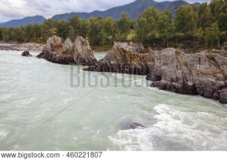 A Fast-flowing Wide And Full-flowing Mountain River. Large Rocks Stick Out Of The Water. Big Mountai