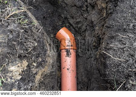 An Orange Plastic Pipe From A Septic Tank With A Diameter Of 160 Mm Lying In A Ditch.