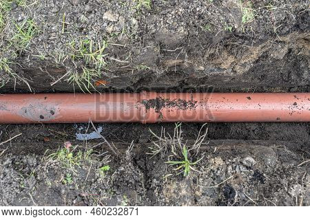 An Orange Plastic Pipe From A Septic Tank With A Diameter Of 160 Mm Lying In A Ditch.