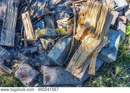 Close-up Of An Unlit Campfire Against Gray And Black Extinguished Ashes, Stones Surrounding Wooden L
