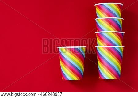 Rainbow Colored Paper Cups On A Red Background. The Concept Of Gay Pride, Lgbt Community, Adoption A