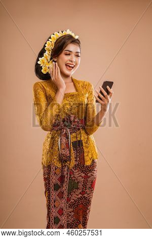 Suprised Balinese Woman With Kebaya While Looking At Her Mobil Phone Screen