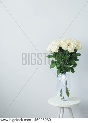 Beautiful Bouquet Of White Blooming Roses In Glass Vase On The White Wall Background. White Flowers 