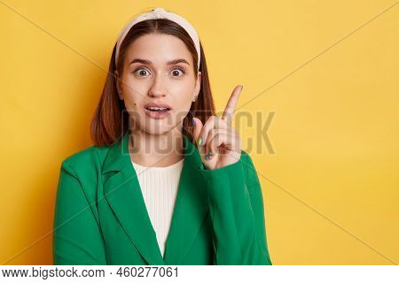 Portrait Of Astonished Beautiful Woman Wearing Green Jacket And Hair Band Posing Isolated Over Yello