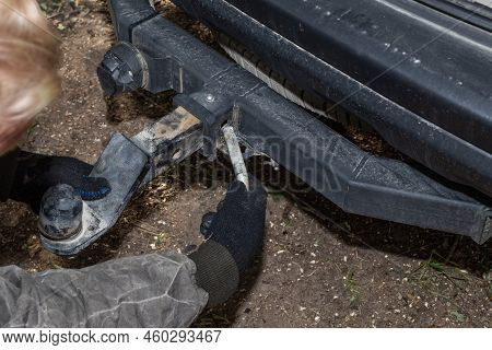 A Man Mounts An Iron Towbar On A Car For Towing A Trailer. Device For Transportation.
