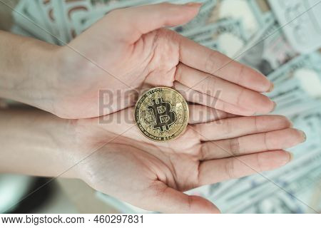 Close Up Of Hand Woman Holding Gold Bitcoin Crypto Currency Blockchain On Dollar Bill Background On 