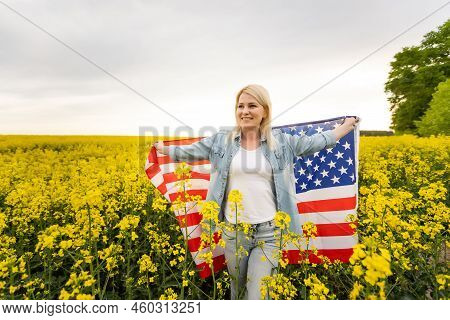 Adult Woman Holding American Flag With Pole, Stars And Stripe In A Yellow Rapeseed Field. Usa Flag F