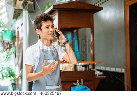 Male Merchant Makes A Call Using A Mobile Phone