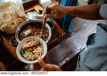 Close Up Of Sellers Hand Put Chicken Over Noodles