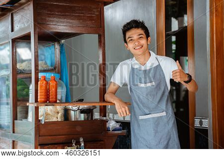 Smiling Young Man Wearing Apron With Thumbs Up
