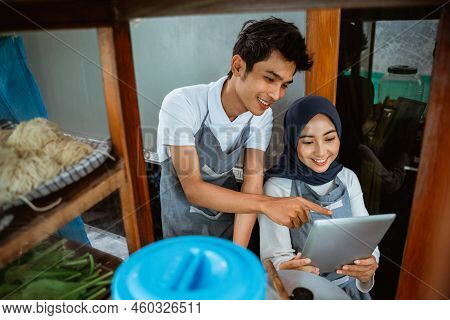 A Couple Of Seller In Aprons Using Tablet Digital