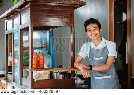 Smiling Young Asian Man Wearing Apron Standing Beside Cart