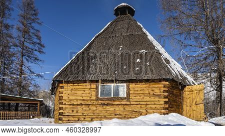 Traditional Altai Village House- Ail. A Hexagonal Wooden Building With A Pyramidal Roof On A Blue Sk