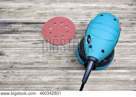 Random Orbital Sander On Wooden Background With Sanding Disc.