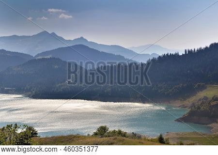 Lake Of Roselend And Blue Turquoise Water Borded By Mountains At Sunset In French Alps