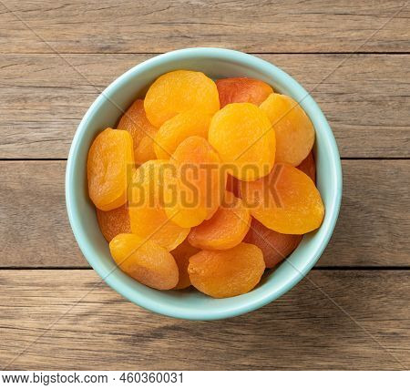 Dried Apricots In A Bowl Over Wooden Table.