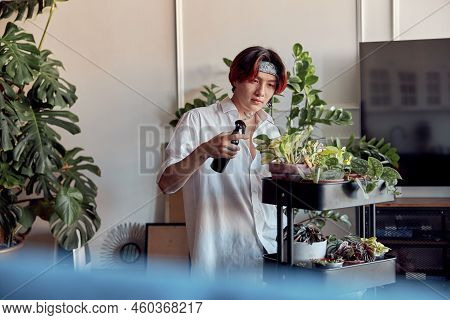 Asian Man Caring And Spraying Water On Indoor House Plant