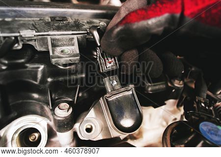 The Auto Mechanic Is Unplugging The Ignition Coil Of The Car Engine In The Engine Compartment.