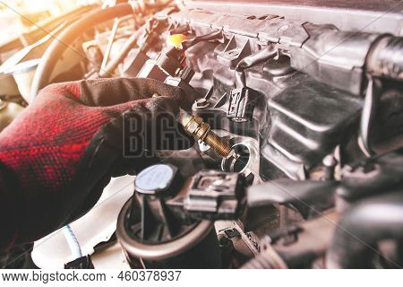 A Auto Mechanic Is Installing Automobile Iridium Spark Plugs Into The Ignition Socket Of The Engine 