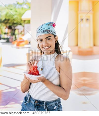Portrait Of Smiling Girl Holding Shaved Ice In The Street. Young Woman Holding A Cup Of Shaved Ice O